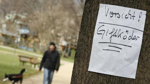 Ein Zettel warnt in einem Park vor Giftködern